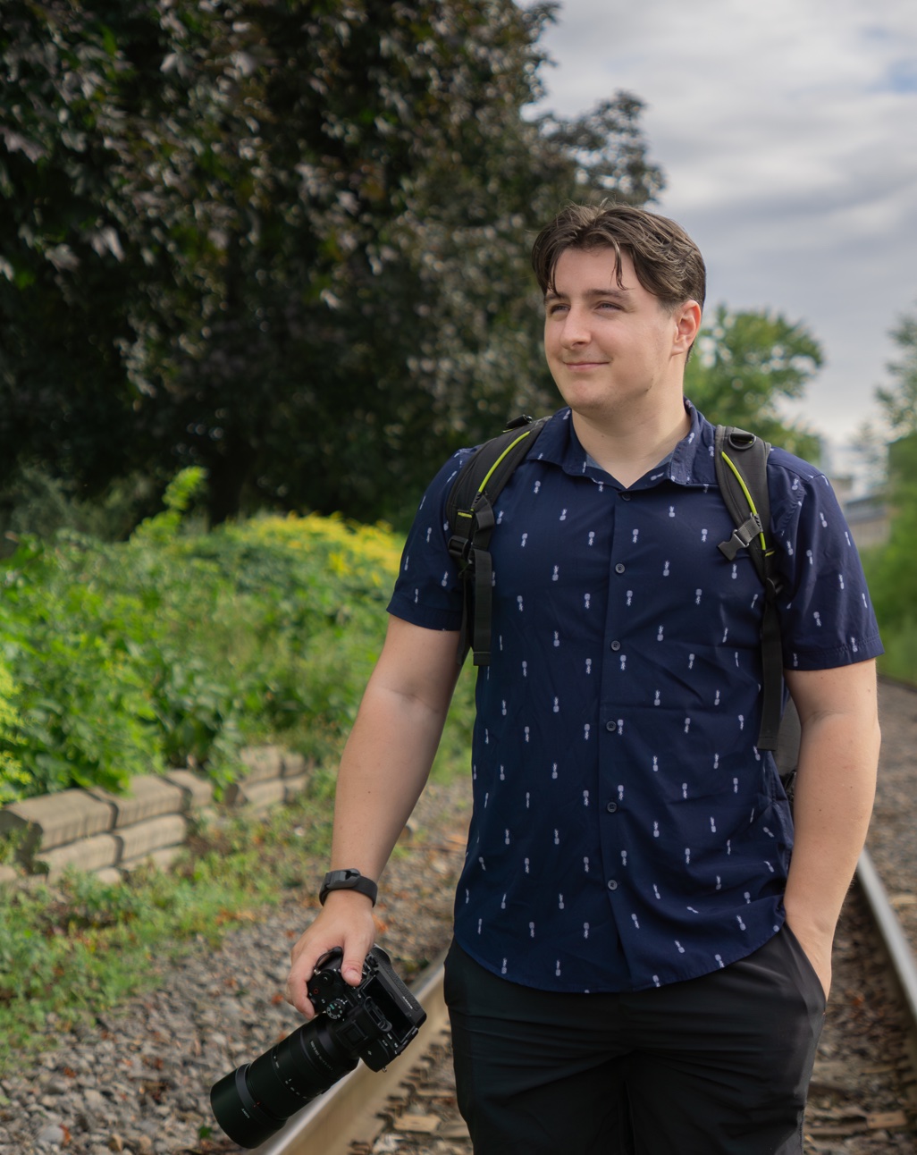 McKenzie Aitken, Eastside Photography founder, holding a Sony camera on train tracks in Prince Edward Island